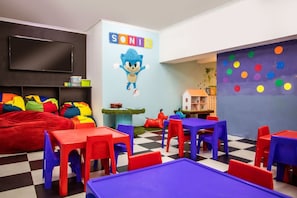 Ein Spielzimmer für Kinder mit bunten Möbeln, Wandmalerei und Fußboden in Schachbrettoptik.