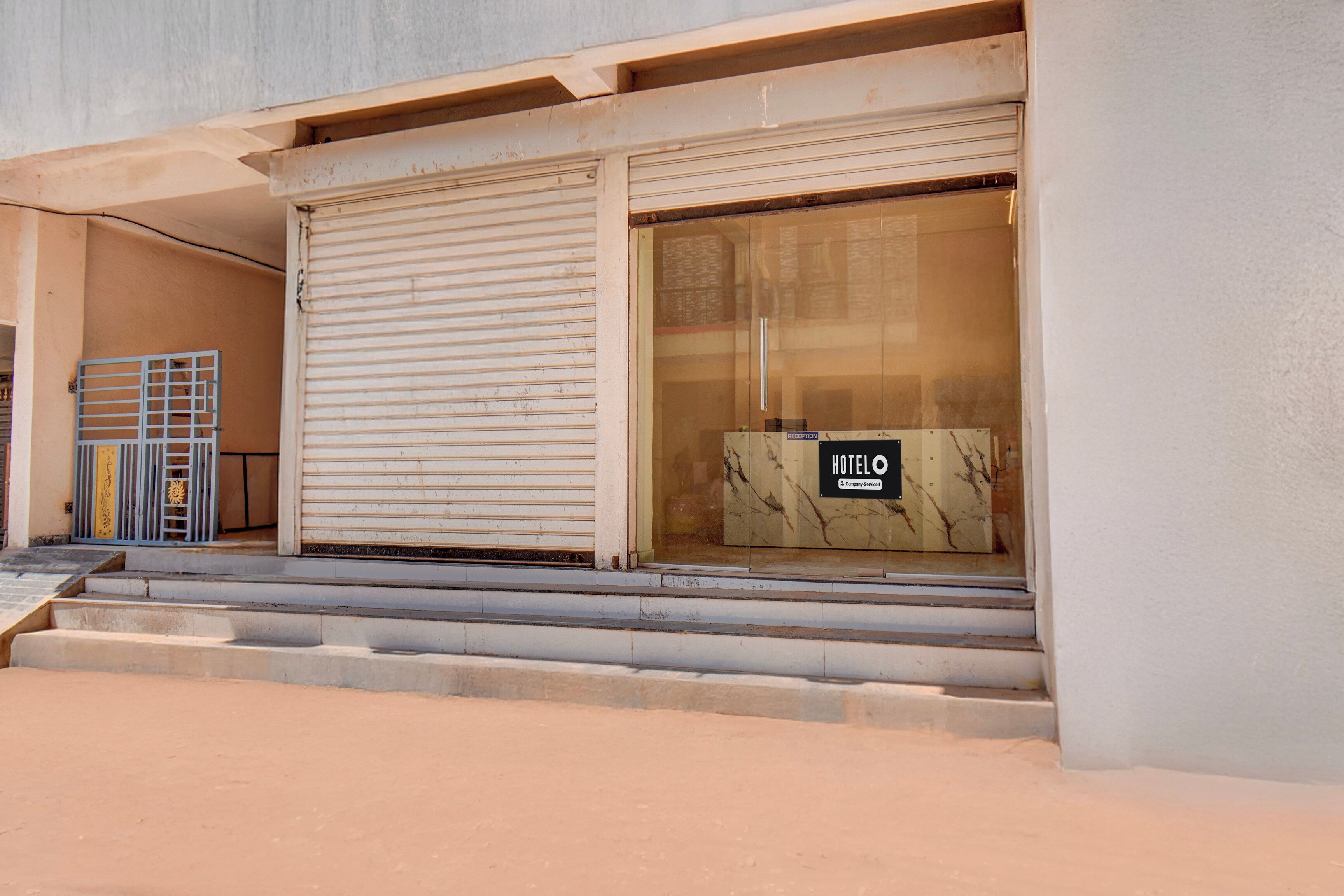 A hotel entrance with a closed shutter, a reception desk, and a staircase leading up.
