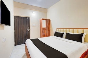A bedroom with a bed, a wardrobe, a mirror, and a television. - Super Hotel O Dehu Pune (Pune)