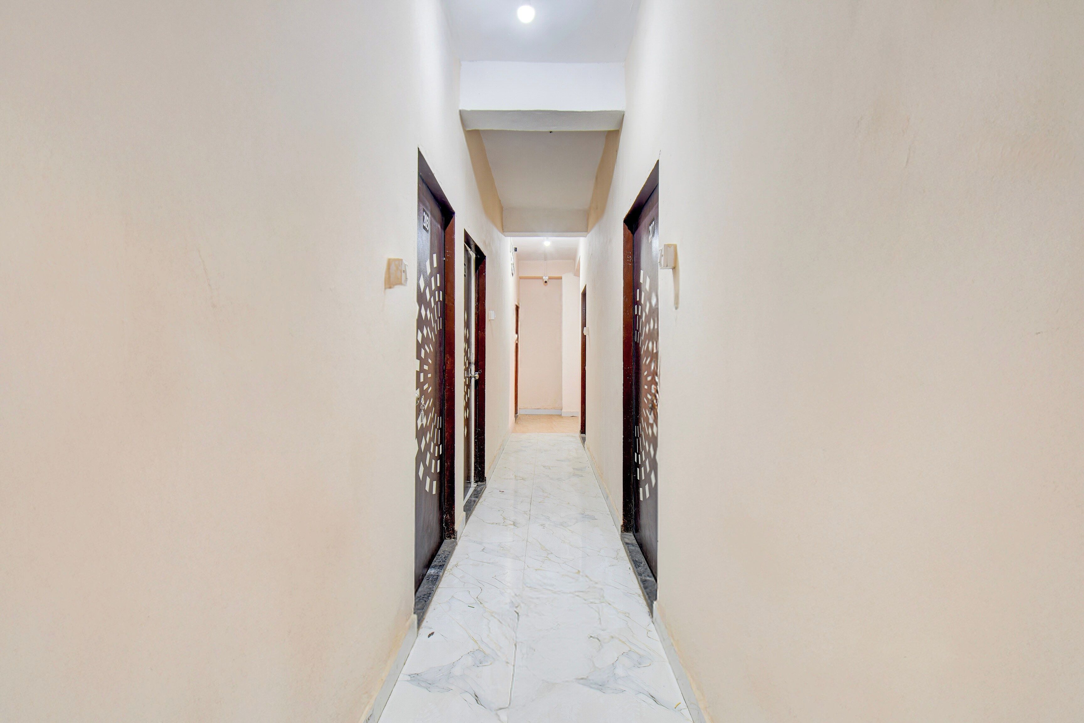 A corridor with marble flooring leading to a door with a number plate.