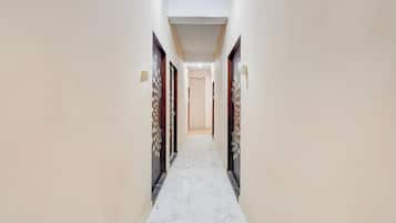 A corridor with marble flooring leading to a door with a number plate.