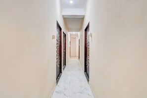Un pasillo con piso de mármol que conduce a una puerta con una placa de número.
