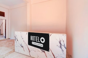 A reception desk with a marble top and a sign indicating it is a company-serviced hotel. - Super Hotel O Dehu Pune (Pune)