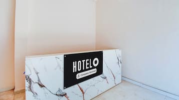 A hotel reception desk with a marble top and a sign indicating it is company-serviced.