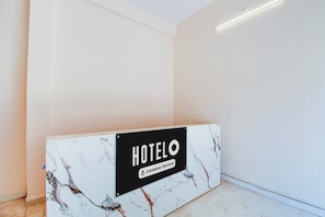 Mostrador de recepción de hotel con encimera de mármol y un letrero que indica servicio de empresa.