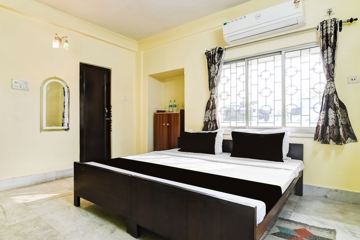 Un dormitorio con cama, aire acondicionado, ventana con cortinas, armario y espejo.