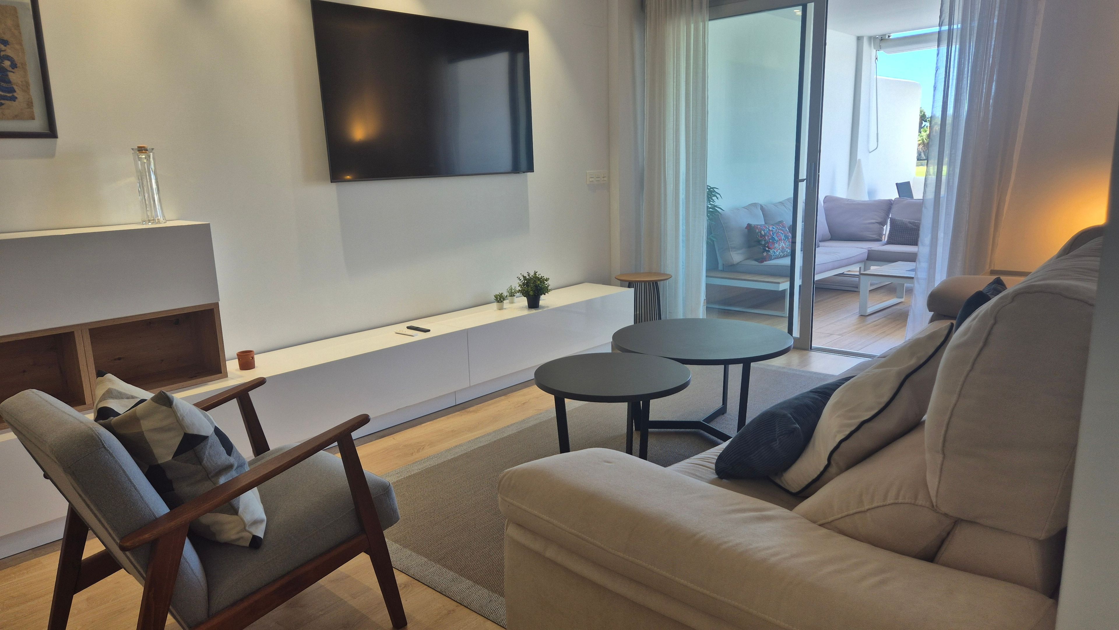 Una sala de estar moderna con un sofá, un sillón y un televisor montado en la pared.