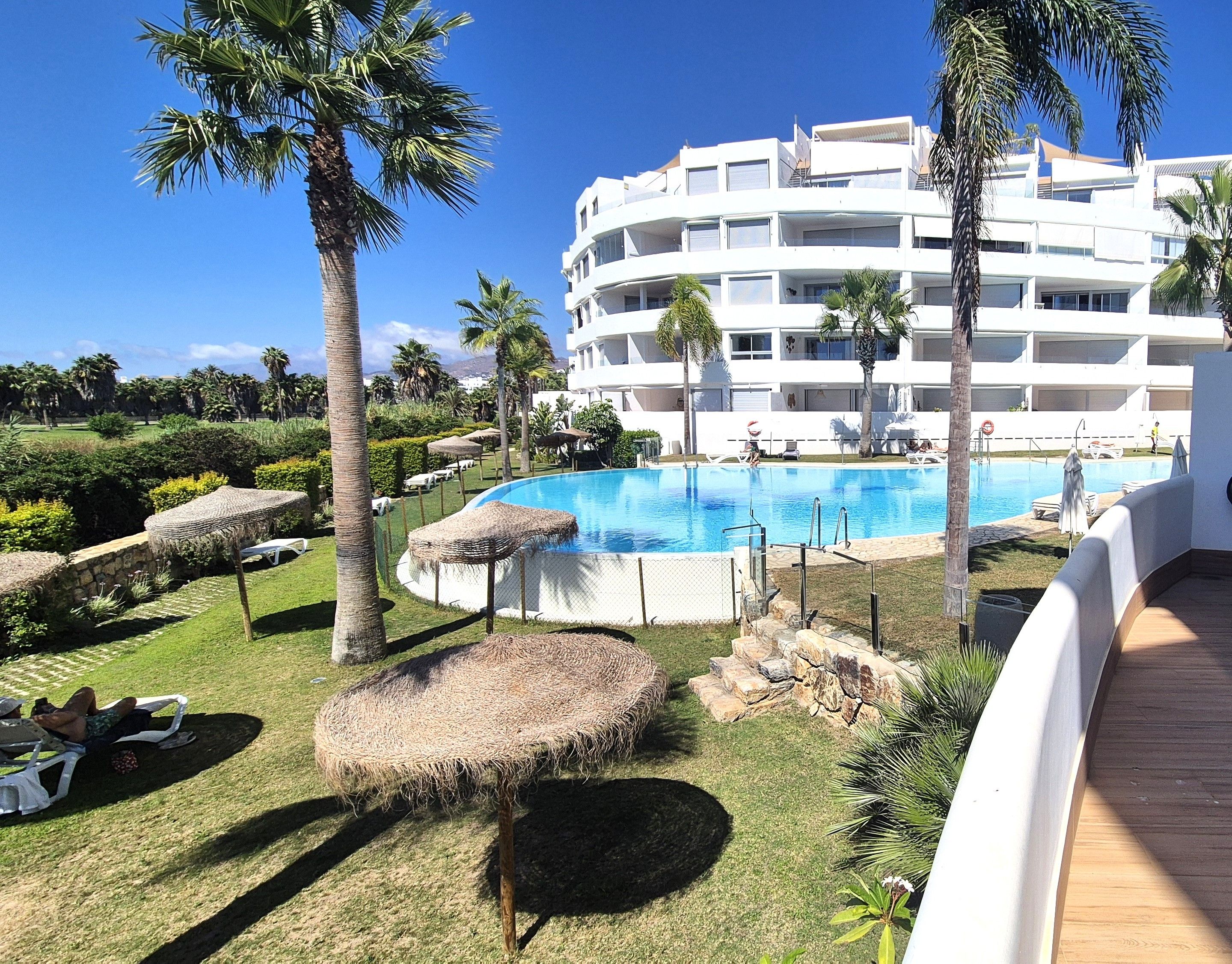 Ein Resort mit Pool, Palmen und einem weißen Gebäude mit Balkonen.