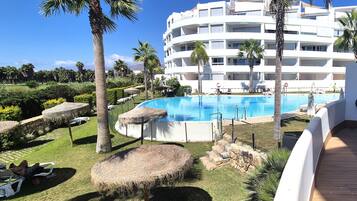 Ein Resort mit Pool, Palmen und einem weißen Gebäude mit Balkonen.