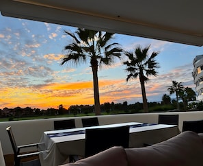 Un espace repas offrant une vue sur les palmiers et un coucher de soleil.