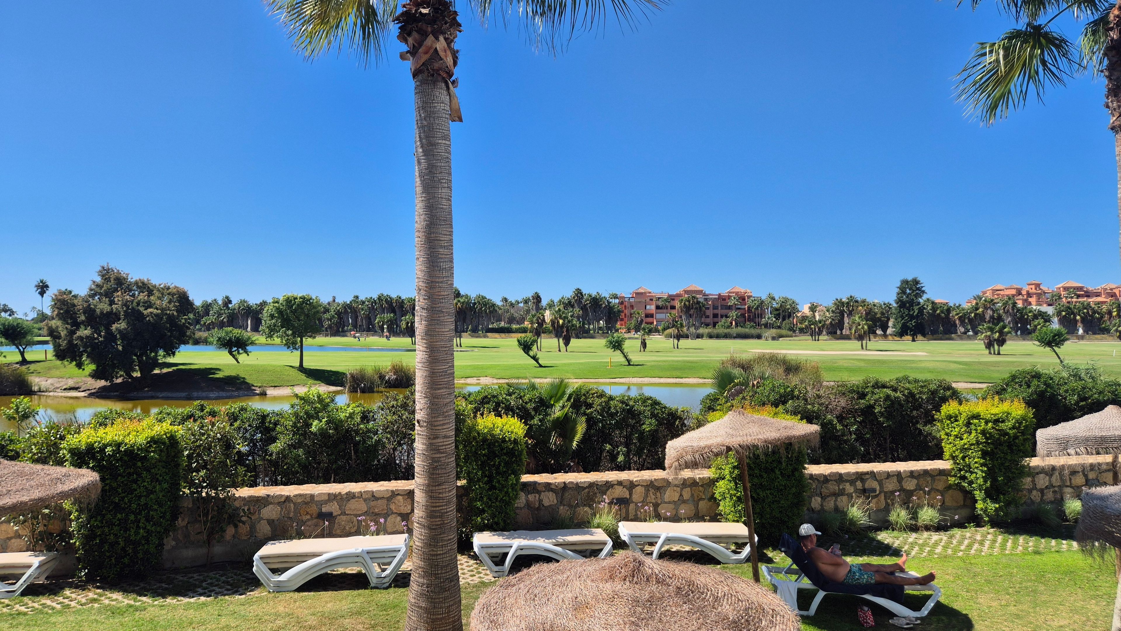 Ein Golfplatz mit Pool, Liegestühlen und einer Steinmauer.