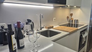 Una cocina moderna con un lavamanos de acero inoxidable, una botella de vino y un vaso.
