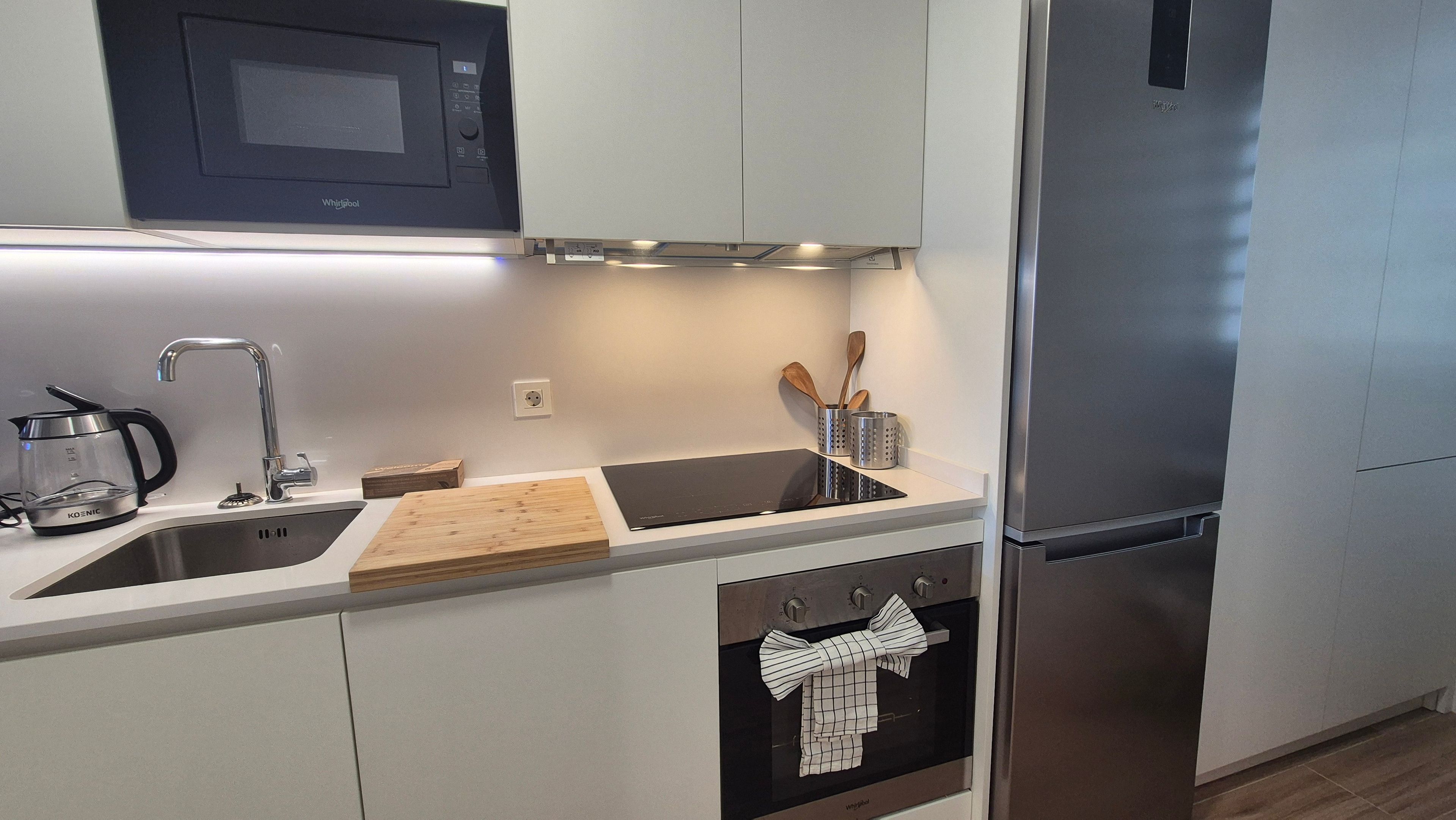 Una cocina moderna con un refrigerador de acero inoxidable, un microondas y un horno empotrado.