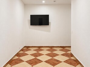 A room with a tiled floor, a flat-screen TV mounted on the wall, and a light switch on the wall. - Your Vienna Home 1BR and Living Room (Wien)