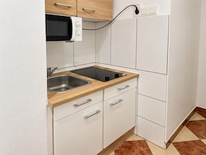 A compact kitchen with a microwave, sink, and a built-in stove. - Your Vienna Home 1BR and Living Room (Wien)