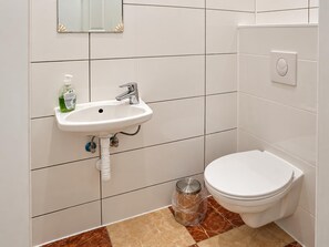A bathroom with a white sink, a toilet, and a trash bin. - Your Vienna Home 1BR and Living Room (Wien)