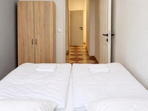 Une chambre d’hôtel avec deux lits, une armoire en bois et un sol à carreaux.