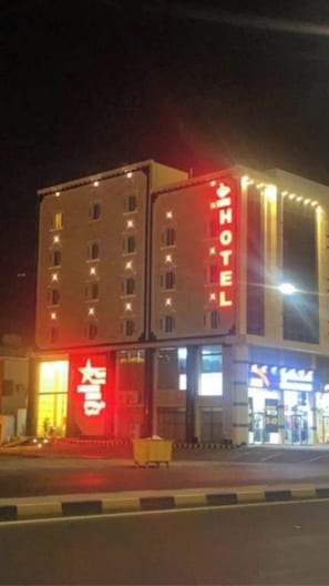 A hotel with a prominent red sign, multiple floors, and a visible entrance.