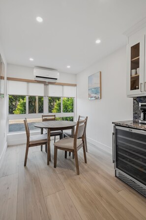 Una cucina moderna con zona pranzo, ampie finestre e vista sul verde.