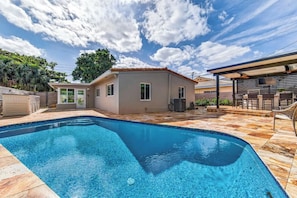 A swimming pool with a tiled deck, a small building with a window, and a covered patio area. - The Cabana Club-3BR- Fantastic Outdoor Pool-Bar-TV (Fort Lauderdale)