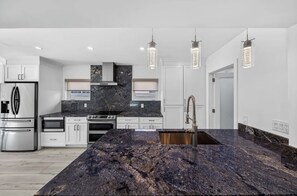 A modern kitchen with granite countertops, stainless steel appliances, and pendant lighting. - The Cabana Club-3BR- Fantastic Outdoor Pool-Bar-TV (Fort Lauderdale)
