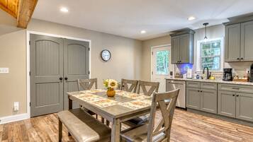 Un coin repas avec une table dressée pour quatre personnes, un banc et une horloge au mur.