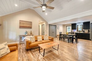 Un vaste espace de vie doté d’un plancher en bois, d’un canapé, d’une table basse et d’une table à manger avec des chaises.