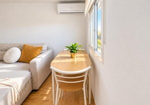 A modern living room with a sofa, a small table with a plant, and a window providing a view. - New Listing (Íllora)