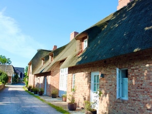 A row of traditional brick houses with thatched roofs and potted plants in front. - 6 St. Barth in the Boldix House (Wyk auf Foehr)