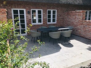 A patio with a table and chairs, a brick wall, and a window. - 6 St. Barth in the Boldix House (Wyk auf Foehr)
