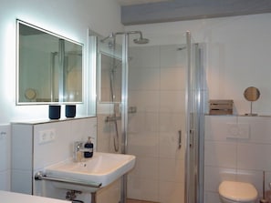A bathroom with a glass-enclosed shower, a white sink with a soap dispenser, and a toilet. - 6 St. Barth in the Boldix House (Wyk auf Foehr)