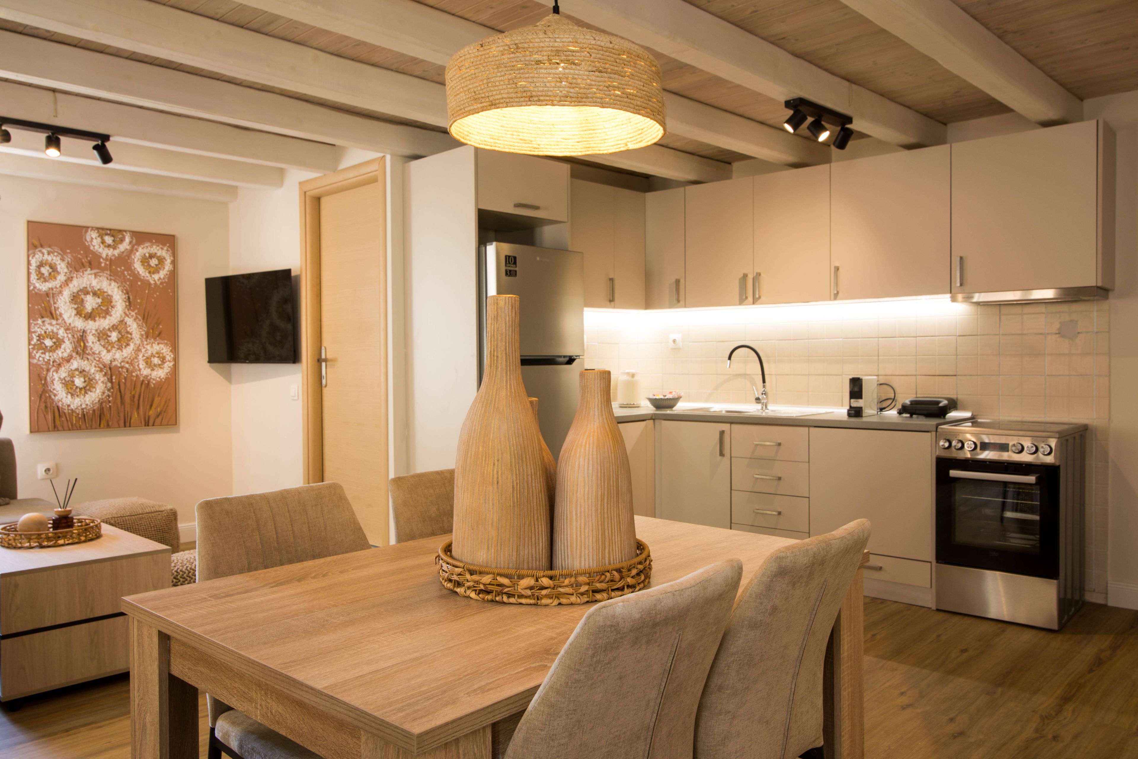A modern kitchen with white cabinets, a stainless steel oven, and a dining area with a wooden table and chairs.