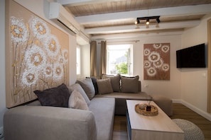 A modern living room with a sofa, a coffee table, and artwork on the walls. - Alto Loft by CorfuEscapes (Corfu)
