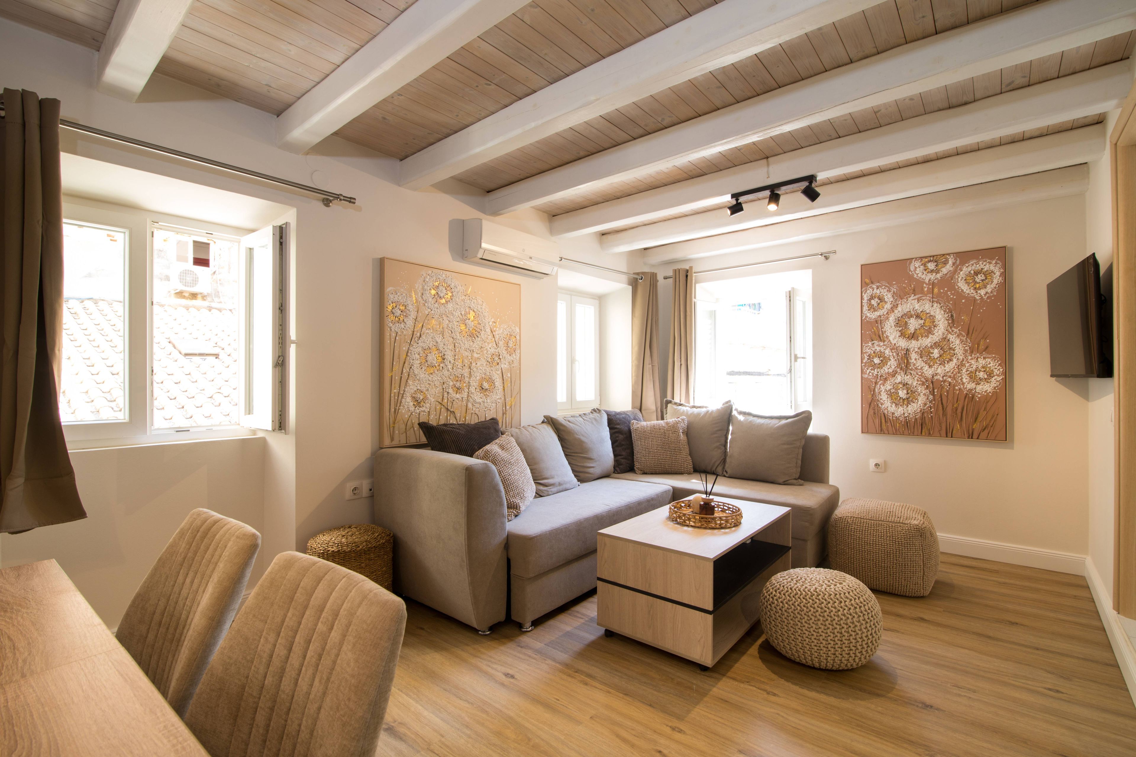 A modern living room with a sectional sofa, a coffee table, and a flat-screen TV mounted on the wall.