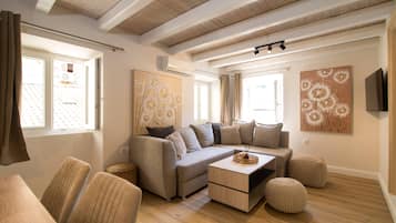 A modern living room with a sectional sofa, a coffee table, and a flat-screen TV mounted on the wall.