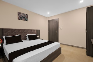 Un dormitorio con una cama grande, cabecera, una puerta y una lámpara fijada a la pared.
