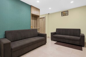 A living room with two dark sofas, a teal accent wall, a wooden cabinet, and a small decorative item on the wall.