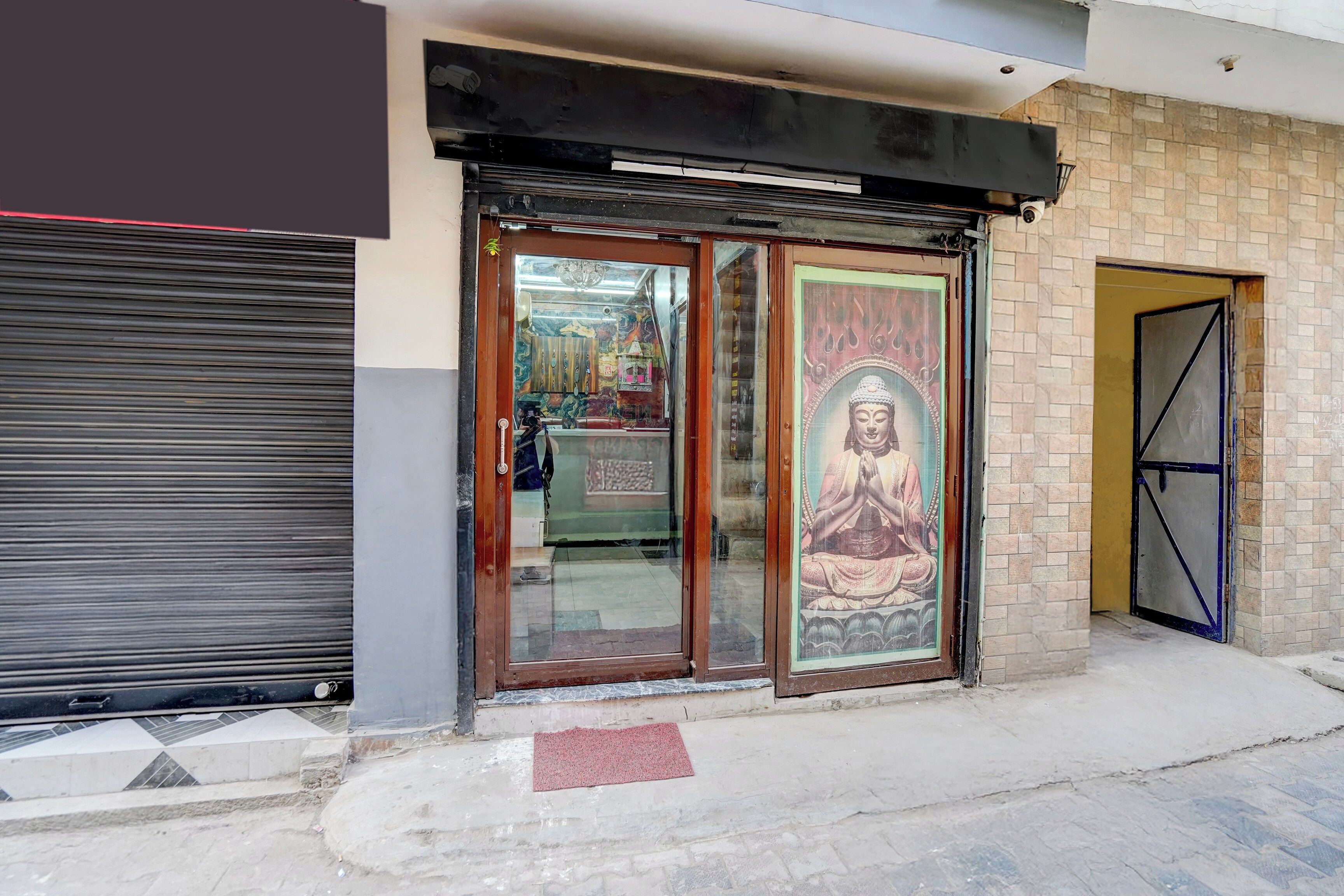 Un edificio con una puerta con contraventanas cerradas, una gran estatua enmarcada de Buda y un acceso con azulejos.