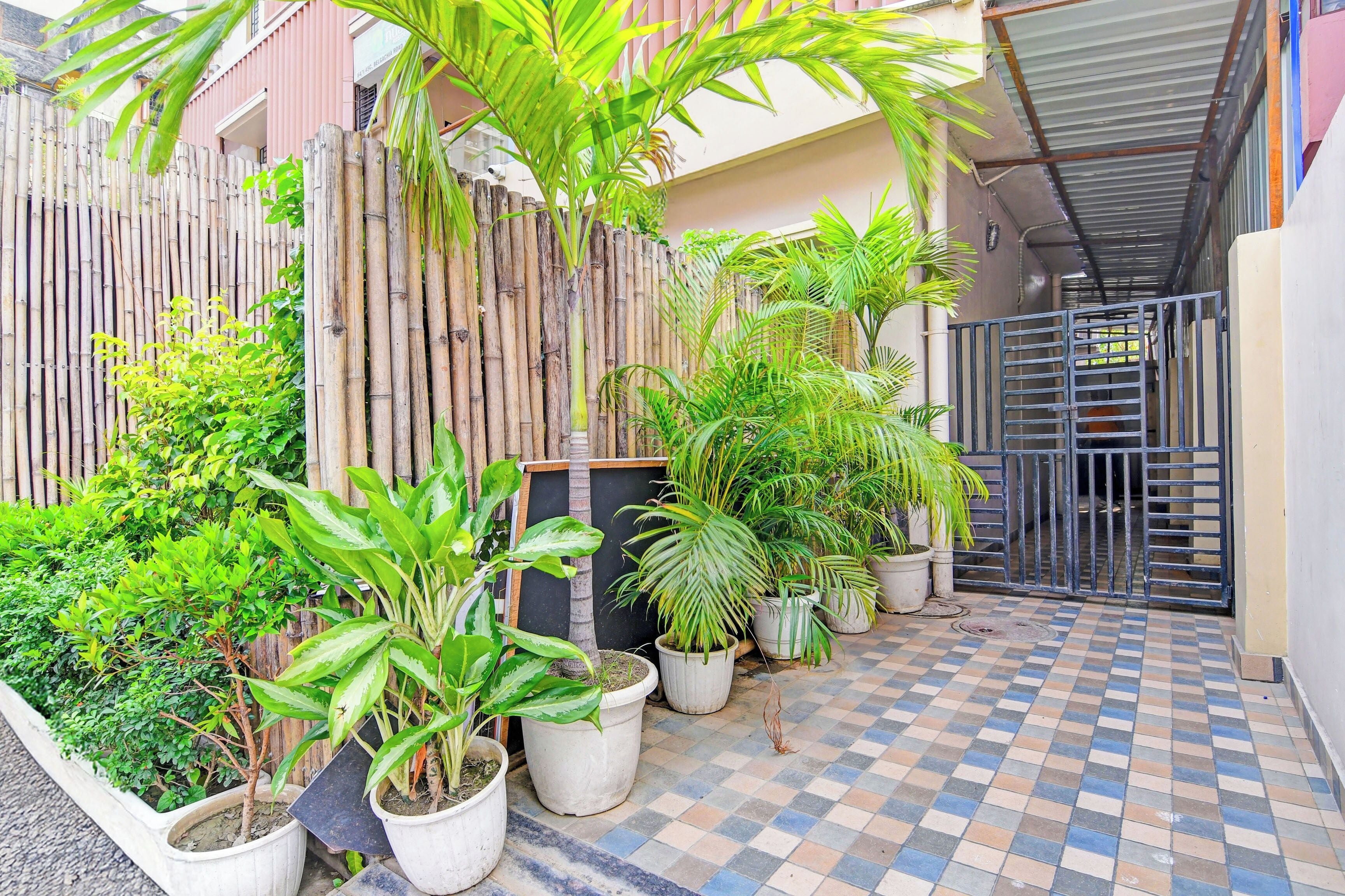 A courtyard with potted plants, a bamboo fence, and a tiled floor.