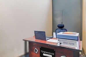 A reception desk with a laptop, a printer, and a sign indicating it is a company-serviced location.