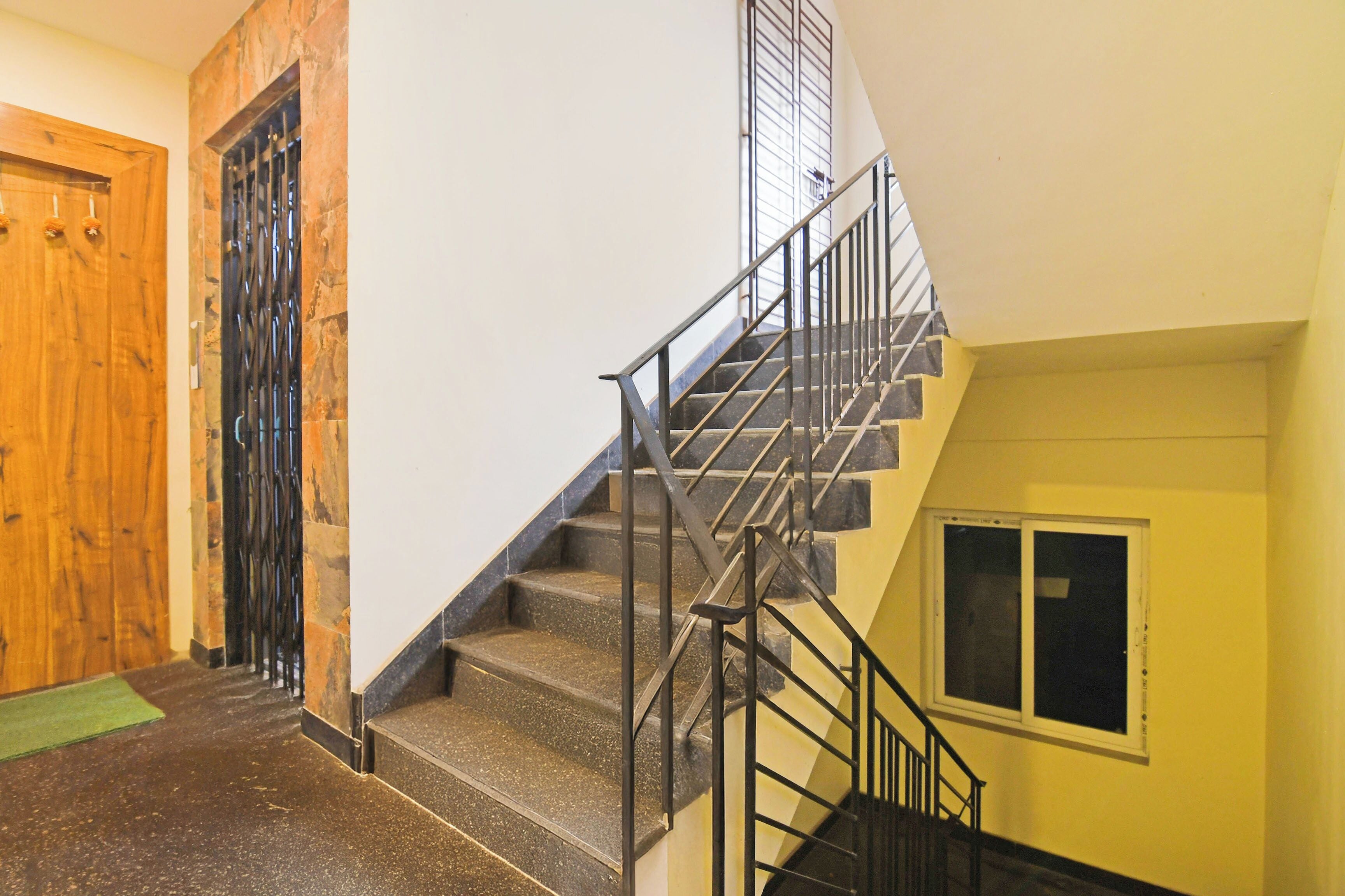 Una escalera con barandales de metal y una puerta de madera a la izquierda.