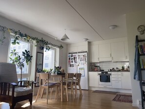 Eine moderne Küche mit weißen Schränken, ein Essbereich mit Holzkästen und ein mit Fotos beklebter Kühlschrank.