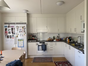 Eine moderne Küche mit weißen Schränken, einem Kühlschrank mit Magneten, einem Herd und einer Spüle.