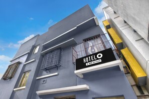 A hotel building with a sign indicating it is serviced by OYO.