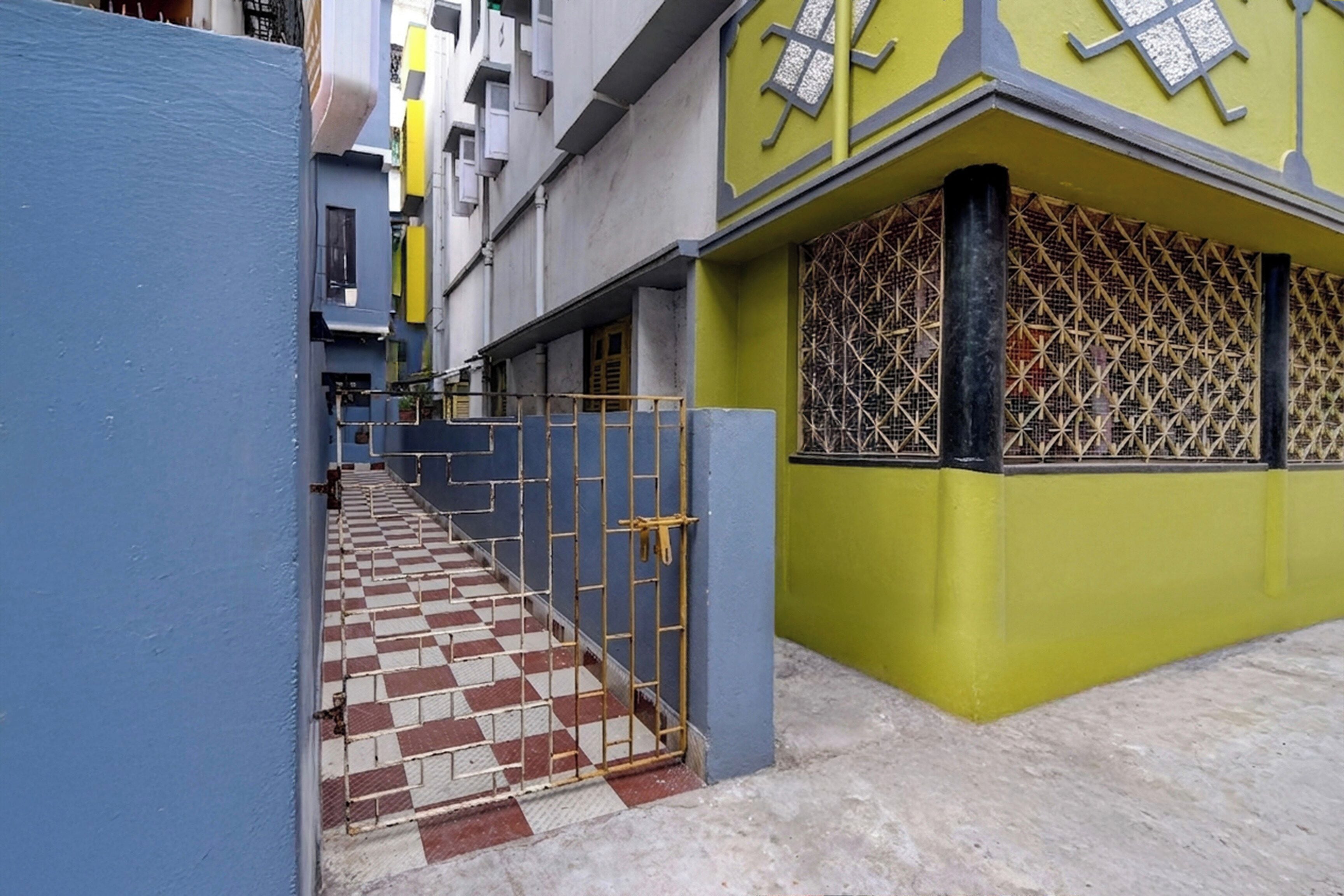 A narrow alleyway with a checkered tile floor leading to a gated entrance.