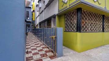 A narrow alleyway with a checkered tile floor leading to a gated entrance.