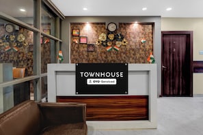 Un taulell de recepció amb un cartell que diu 'TOWNHOUSE' i 'OYO-Serviced'.