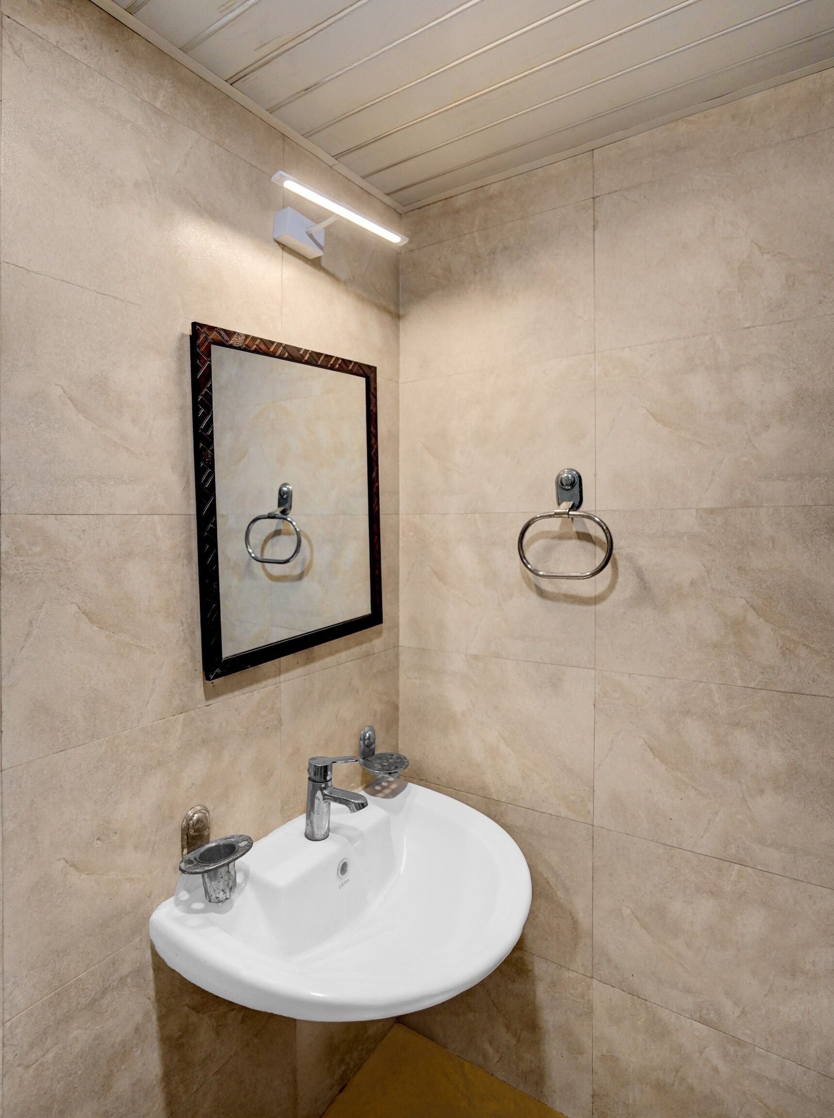 A bathroom with a white sink, a mirror, and two towel rings.