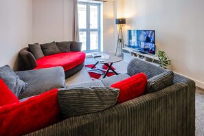 Een moderne woonkamer met een modulaire bank, een salontafel en een flatscreen televisie.