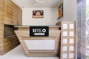 Un comptoir d’accueil d’hôtel avec une enseigne « HÔTEL », un lambris en bois et un ventilateur de plafond.